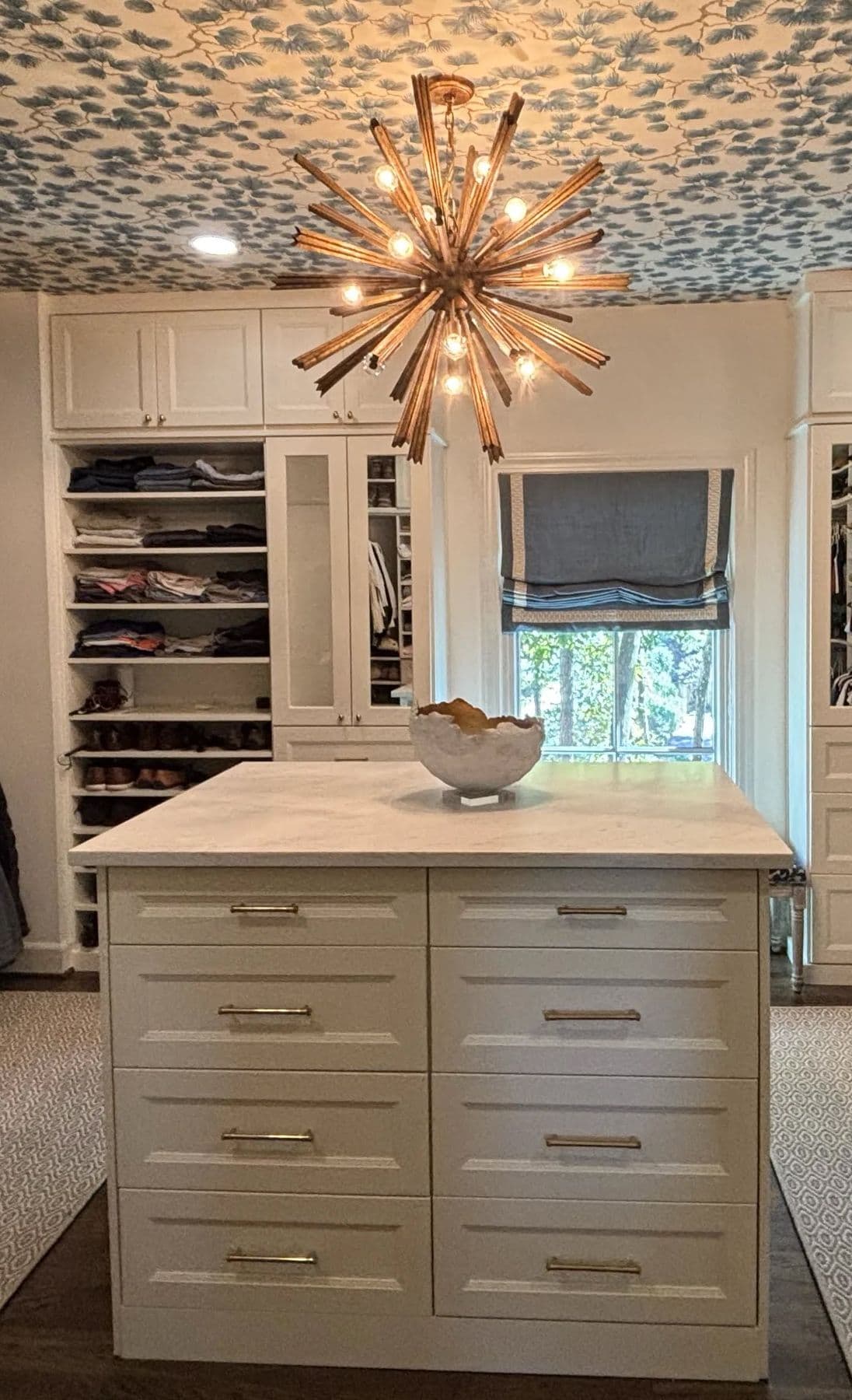 Closet island with drawers under a starburst chandelier